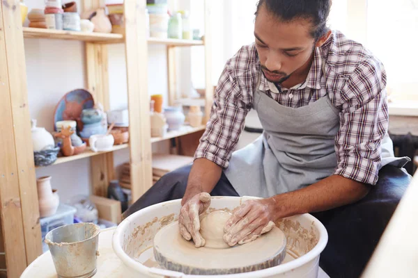 Creative craftsman making pottery on special equipment in workshop