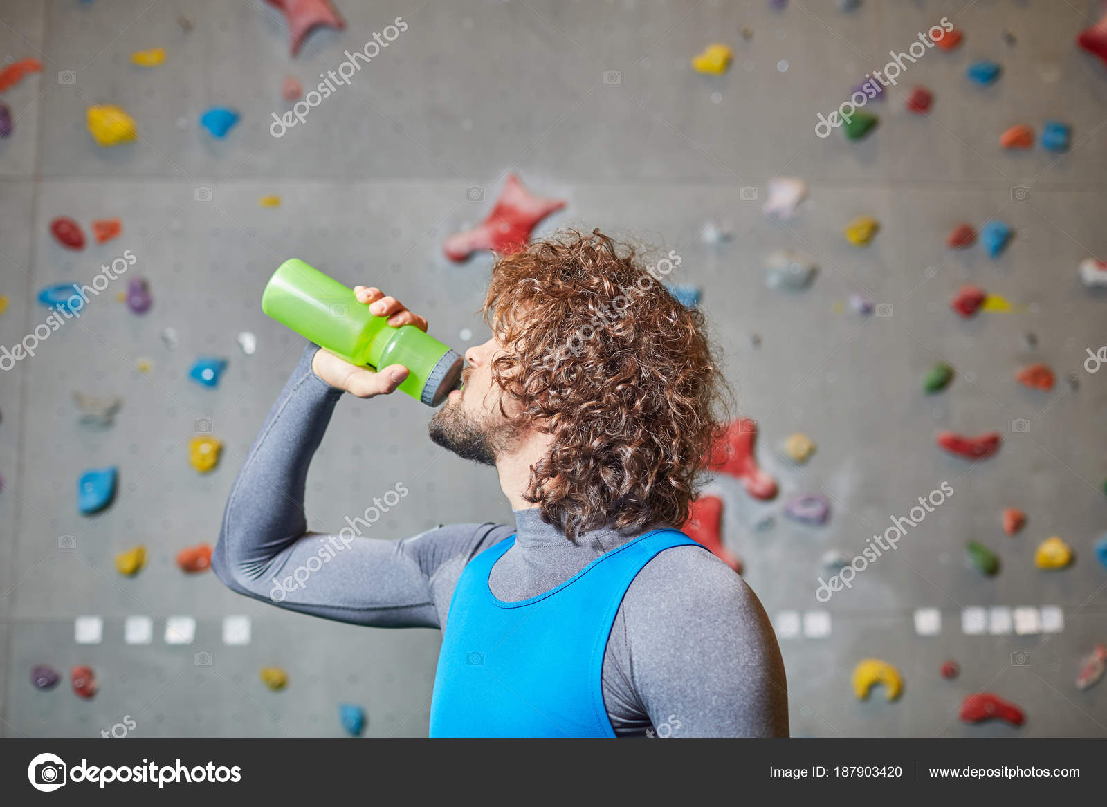 Encaracolado Jovem Beber água Garrafa Fundo Parede Escalada Stock