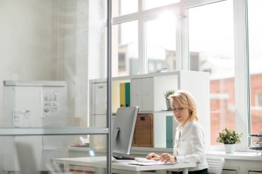 Onun iş yeri tarafından belgeleri okuma konsantre ciddi ofis çalışanı