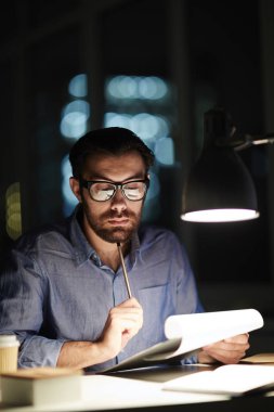 Kalem ve belge metin karanlık Office ile yanan lamba bakarak dalgın işkolik