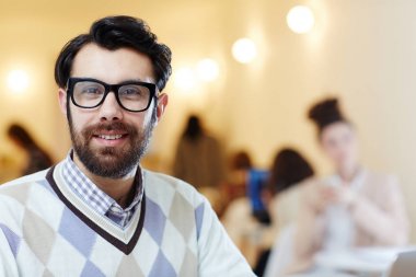 Kameraya bakarak iş sırasında gözlük gülümseyen genç adam