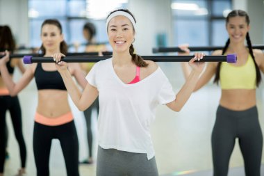 Eğitim bar ve boş olarak spor salonunda egzersiz arka plan üzerinde arkadaşları ile mutlu aktif kadın
