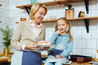 Orta yaşlı kadın, kendi kendine yapılan tatlı ve sevimli torunu mutfakta vakit