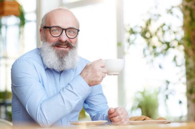Gülümseyen adam ya da fincan çay kafede kahve molası sırasında rahatlatıcı ile işadamı sakallı