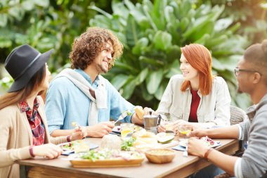 Grup dostu genç erkek ve kadınların şenlikli yemeği Bahçe odasında zevk