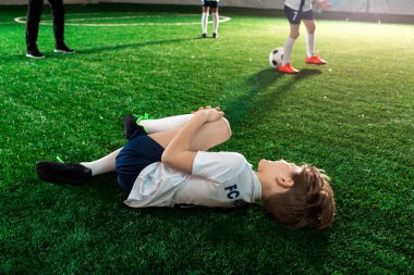 Hitted futbol oyuncu sahada yalan ve tarafından tutarak diz kazadan sonra zarar.