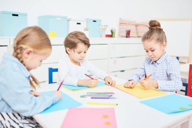Sevimli genç çocuklar tarafından masanın ve anaokulunda boya kalemi ile çizim