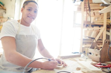 Kameraya bakarak iş sırasında pyrographic makine ile genç kadın