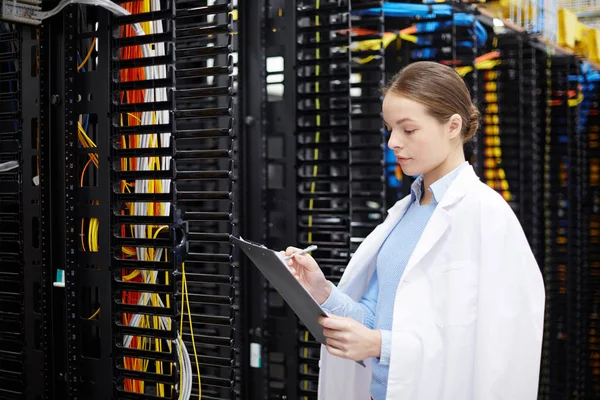 Kadın teknisyeni veya uzman çalışma notları veri merkezinde yapım whitecoat