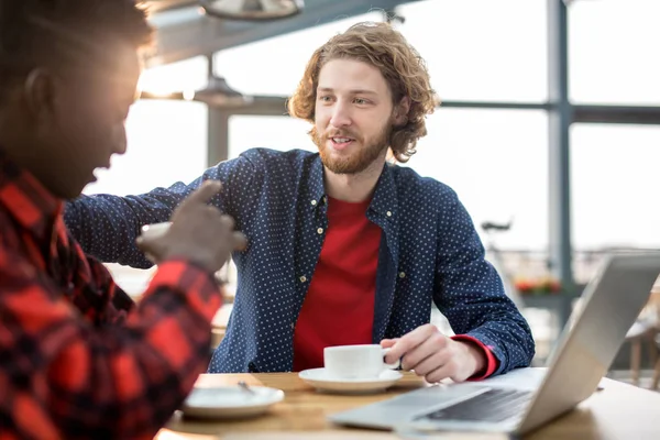 普段着のままカフェで紅茶のカップでの会話中に彼の同僚を支える若い男 — ストック写真