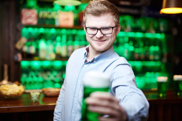 眼鏡のパブでアイルランドのビールのグラスと乾杯で幸せな若い男 — ストック写真