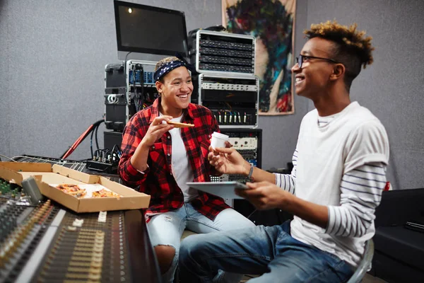 Two sound operators having pizza and coffee in their record studio at lunch break