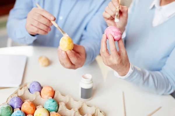 テーブルの上の卵と絵筆を保持しているとイースターの祝祭のための彼らの創造性を表現する人間の手 — ストック写真