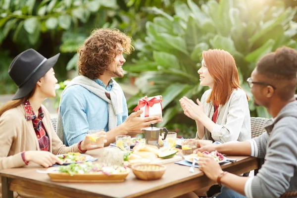 Genç adam hediye kutusu kız arkadaşına arkadaşlarıyla birlikte Festival tablo tarafından verilmesi