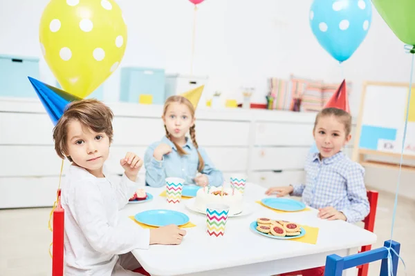 Grupo Niños Adorables Gorras Cumpleaños Sentados Junto Mesa Festiva Con — Foto de Stock