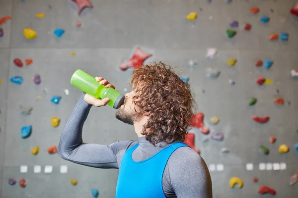 Lockiger Junger Mann Trinkt Wasser Aus Flasche Kletterwand — Stockfoto