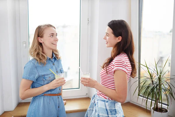 Cam kenarında duran ve ev ortamında konuşurken içecekler ile dostça kız