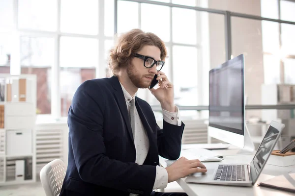 Seriös Affärsman Kostym Talar Till Kollega Smartphone Medan Sitter Desk — Stockfoto