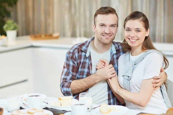 Kameraya gülümsüyor ile tarafından sunulan tablo otururken neşeli ve aşk genç Çift