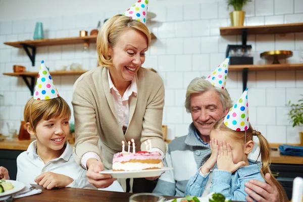小女孩用手捂着眼睛 而她的祖母用生日蛋糕看着她的节日晚餐 — 图库照片