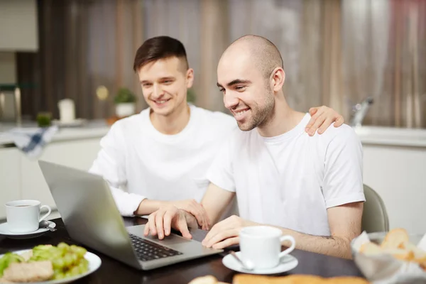 Homoseksualnych Para Siedzi Przy Stole Przed Laptop Oglądanie Wiadomości Online — Zdjęcie stockowe