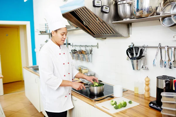 Jonge Vrouwelijke Chef Kok Stukjes Broccoli Pan Met Water Aan — Stockfoto