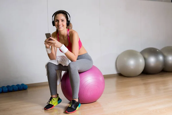 Mutlu Sportif Kadın Fitness Topu Üzerinde Otururken Müzik Smartphone Ile — Stok fotoğraf
