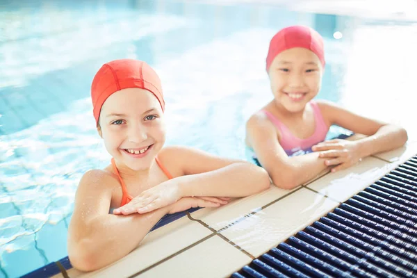 Gelukkig Interculturele Schoolmeisjes Zwemmen Caps Badmode Kijken Camera Zwembad — Stockfoto
