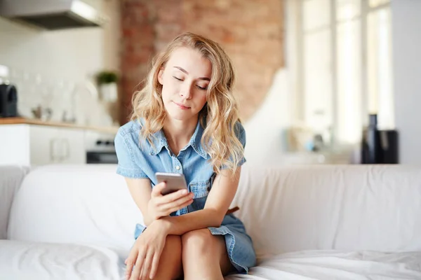 Giovane Donna Seduta Sul Divano Casa Messaggistica Nel Suo Smartphone — Foto Stock