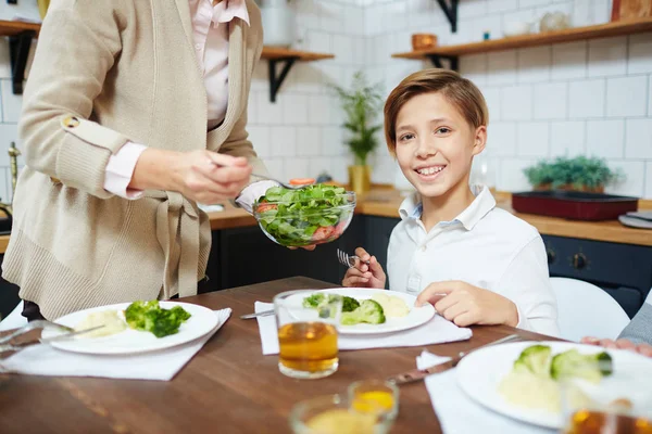 Niño Feliz Mirando Cámara Por Cena Mientras Abuela Pone Ensalada —  Fotos de Stock