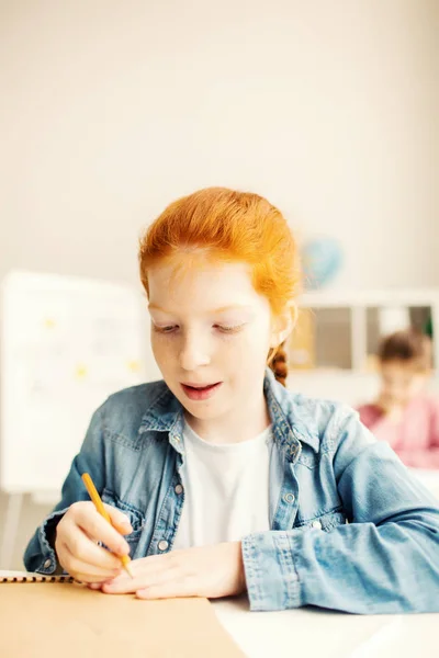 学校的可爱的学习者拿着铅笔在记事本页上 并会画一些东西 — 图库照片