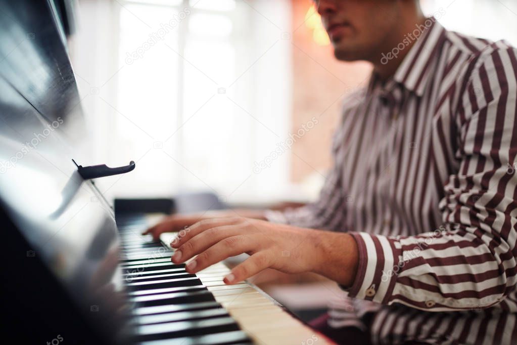 Young man with his hands over piano keys during play