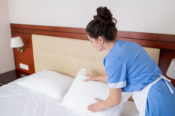 Mavi Üniformalı Esmer Kadın Beyaz Önlüklü Otel Odasındaki Yastıkları Değiştirirken — Stok fotoğraf