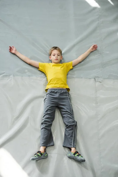 在体育中心训练后 穿着运动服的瘦小男孩躺在灰蒙蒙的垫子上 — 图库照片