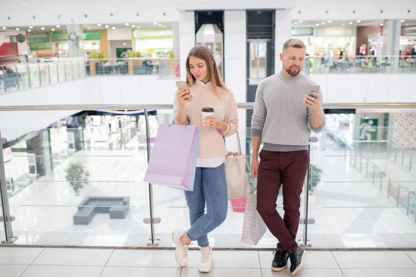 Dos Millennials Ropa Casualwear Desplazándose Los Teléfonos Inteligentes Mientras Que — Foto de Stock