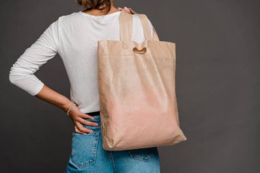 Tişörtlü ve kot pantolonlu genç bir kadının sırtında izole bir şekilde tekstil çantasıyla geziyor.