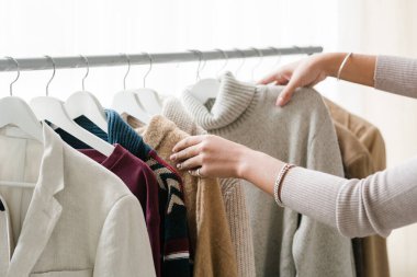 Yeni sezonluk günlük kıyafet koleksiyonundan sıcak örgü ve yün elbiseler seçen genç bayan müşterilerin elleri