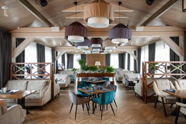 Modern lüks restoranların büyük salonunun içinde servis masaları ve rahat yumuşak kadife koltuklar ve koltuklar var.