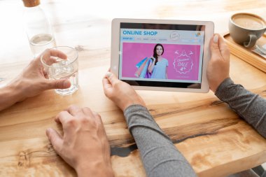 Genç bir kadın dijital tablet tutuyor. İnternetteki ana sayfası erkek arkadaşıyla konuşurken sergileniyor.