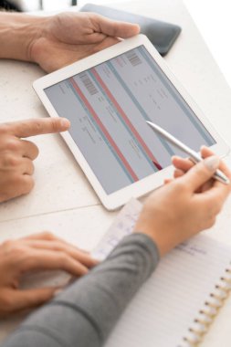 İş toplantısında dijital tablette online mali bilgileri tartışan iki çağdaş meslektaşın elleri