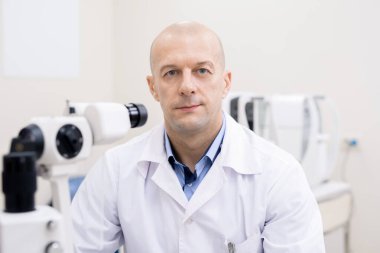 Whitecoat 'ta başarılı bir profesyonel kliniklerde kameranın önünde oturup yeni tıbbi ekipmanlarla çalışıyor.