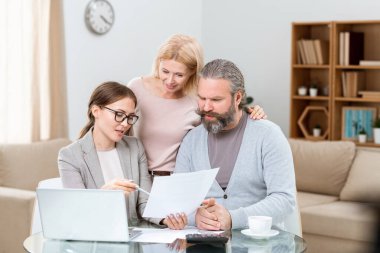 Genç ve sevecen bir çift kağıda bakarken kendine güvenen bir ajan onlara ana noktaları anlatıyor.
