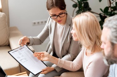 Genç ve olgun kadınlar belgeleri imzalamadan önce müzakere ederken mali harcamalarla kağıt tartışır