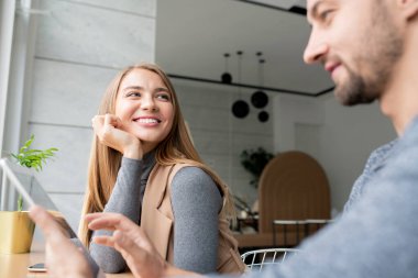 Genç, neşeli iş kadını iş arkadaşının yanında oturuyor. İkisi de Kafe 'de iş projesi üzerinde çalışırken dokunmatik ped kullanıyor.