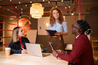 İki genç kültürler arası yönetici, başarılı meslektaşlarının kafede buluştuğu haberini dinliyor.