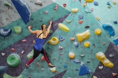 Spor salonunda boş zamanlarında tırmanma ekipmanlarına tutunan genç bir kadın.