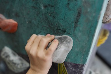 Spor salonunda ya da dinlenme merkezinde eğitim sırasında tırmanma ekipmanlarından birinin üzerinde bir okul çocuğunun eli.