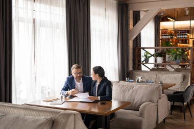 İki başarılı iş ortağı evrakları tartışıyor ve restoranda çalışma anlarıyla ilgili danışmanlık yapıyor.