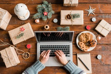 İnternetten Noel hediyesi almak için internette sörf yapan dizüstü bilgisayarlı kadınların elleri.