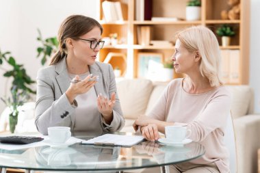 Genç ve zarif muhasebeci, olgun meslektaşına ofiste bir çalışma noktasını anlatıyor.